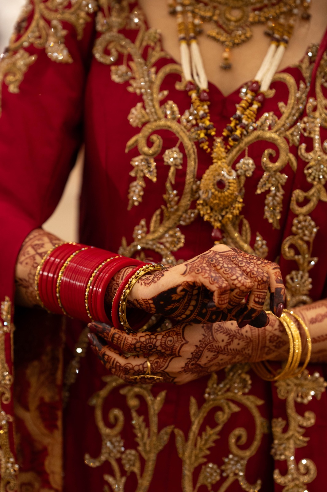 Bridal henna and bangles detail on hand-embellished red bridal couture