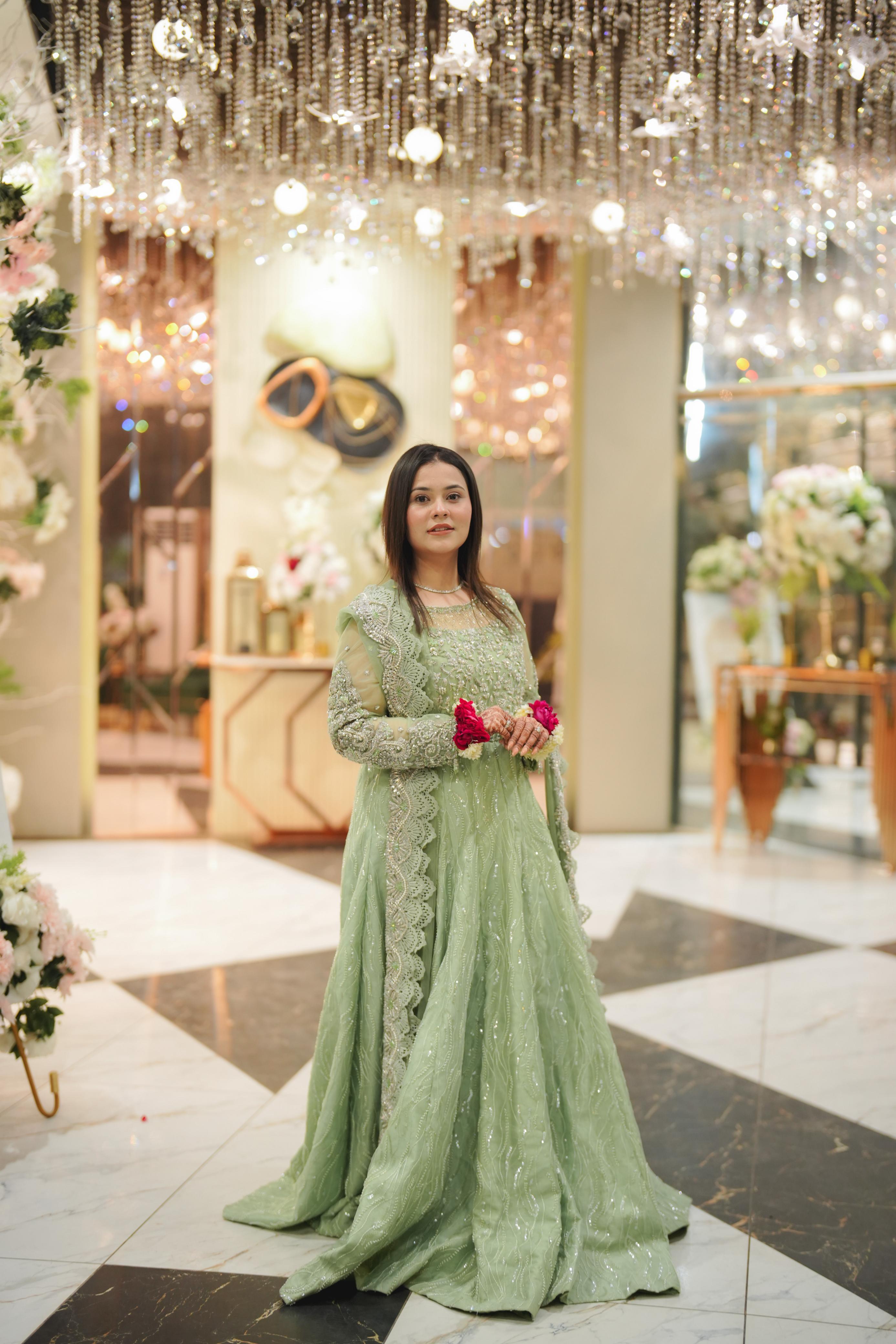 Real client in sage green embellished gown by Sameera's Collection at a chandelier-lit reception